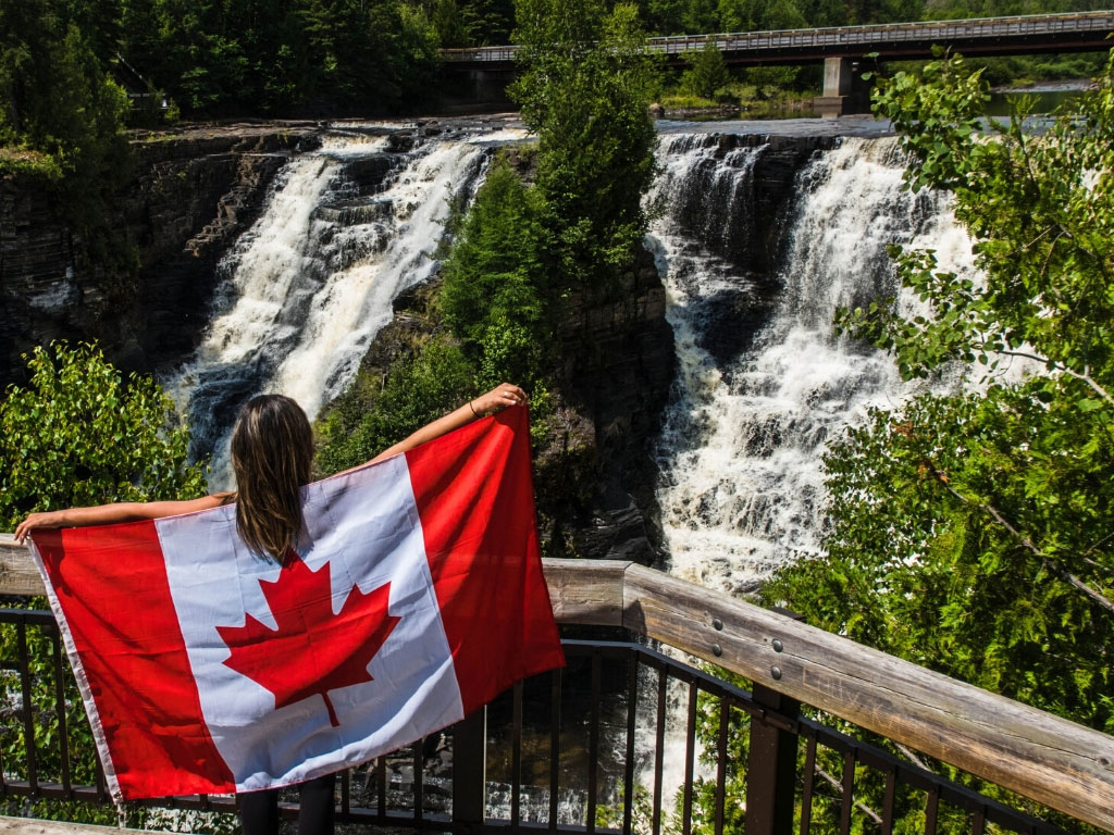 カナダの国旗を背負って自然を眺める少女